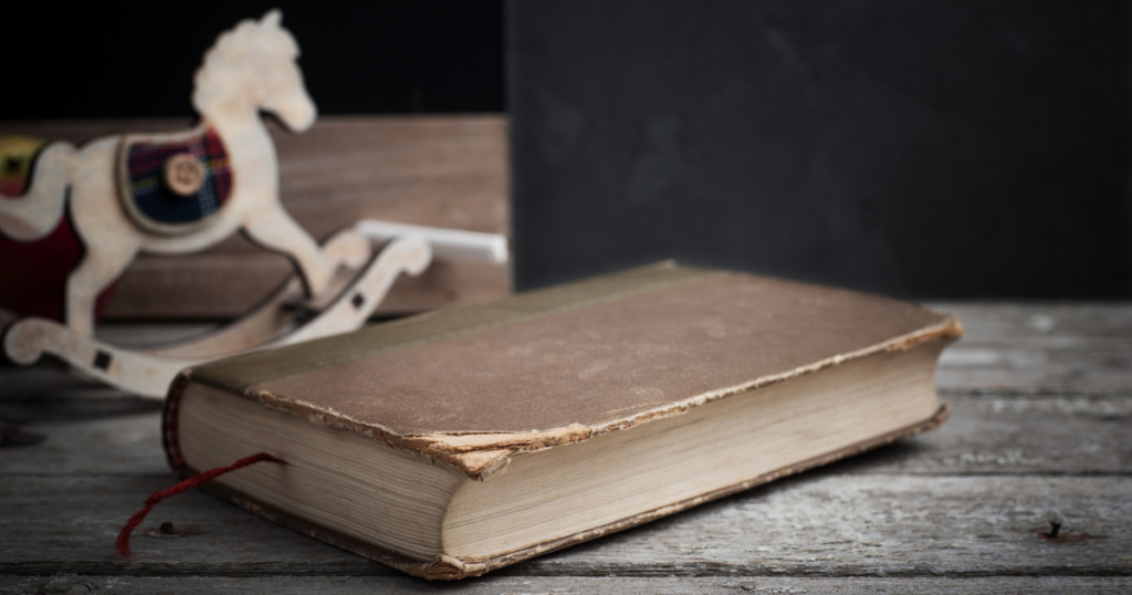 toy wooden horse next to an antique book